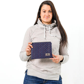A woman holding a dark blue zip pouch with colored lines pattern with a gray Unshattered labe 