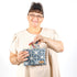 Woman putting cards inside a blue and white geometric patterned pouch named Erica 
