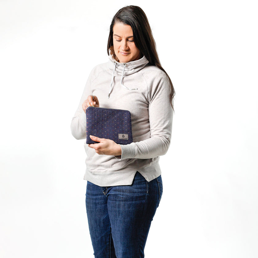 Woman unzipping an upcycled blue fabric zip pouch named Nancy on a white background