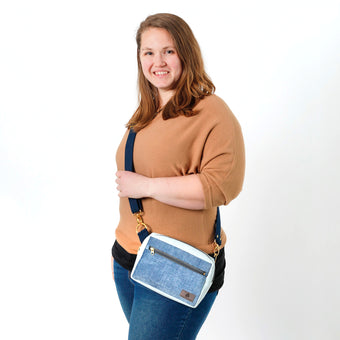 A woman wearing a blue errand bag with blue straps and gold hardware 