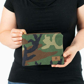 A woman holding a Woodland Camo zip pouch 