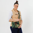 A woman wearing Woodland Camo Crossbody bag featuring a brown Unshattered label and green strap with gold hardware