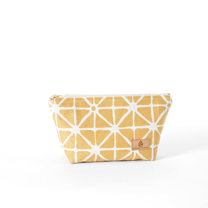 Yellow geometric patterned makeup bag named Isabel with a gold-tone zipper on a white background 