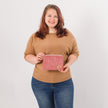 Woman holding a pink zip pouch against a white background