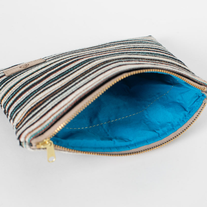 A bright blue fabric interior on this multicolor plush zip pouch with a gold seam and a gold tone zipper.