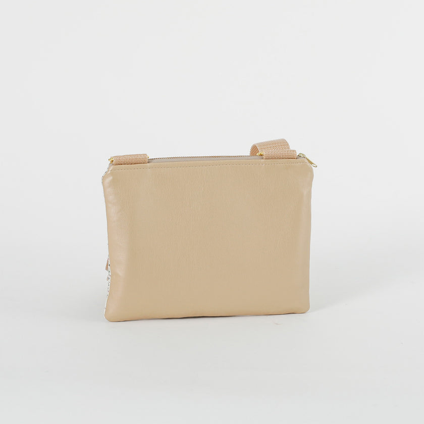A cream wipe-clean back of a crossbody pouch with tan straps on a white background named after Lydia