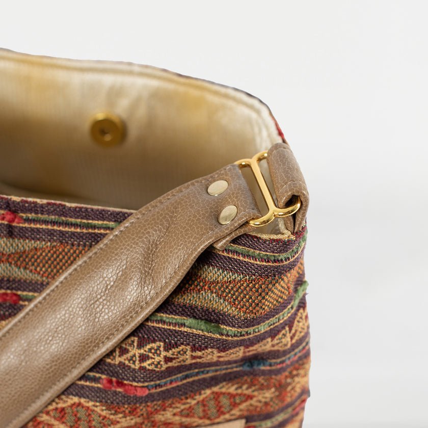 A brown strap with gold hardware named after Chanel Tote 