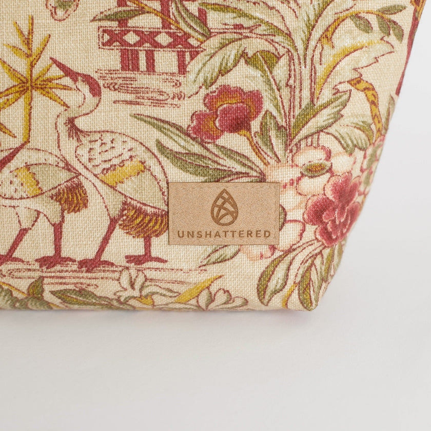 Fabric with floral and bird pattern and 'Unshattered' brand label on a white background named after Anitha 