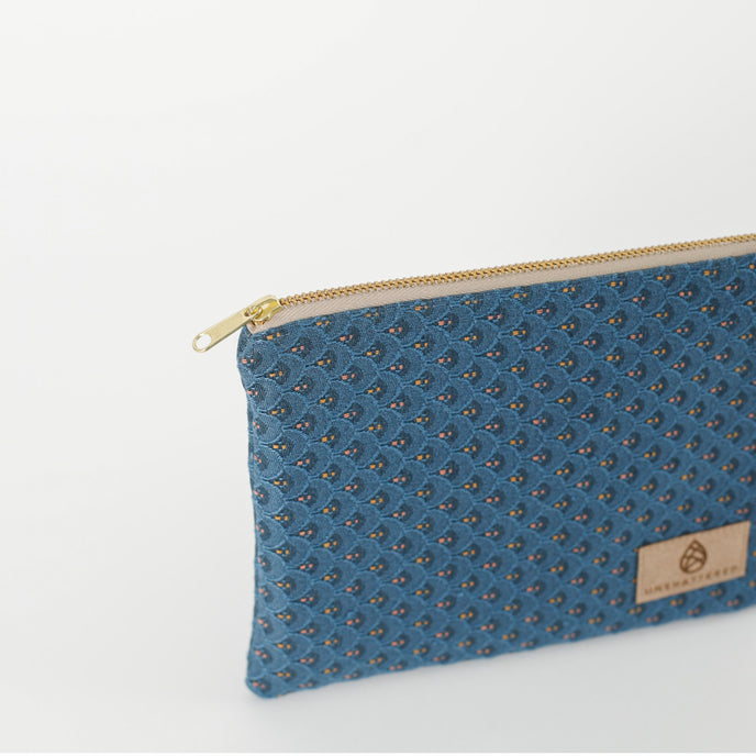A gold tone zipper on a blue zip pouch 