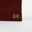 Close up of a brown, ultrasuede Unshattered label on a burgundy floral damask fabric pouch 