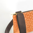 Close-up of an orange textured bag with a brown strap on a white background named after Grace 