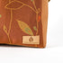 Brown fabric with leaf patterns and 'Unshattered' brand label on a white background named after Nita 