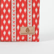 Red and white patterned zip pouch with 'Unshattered' brand label on a white background named after Neena 