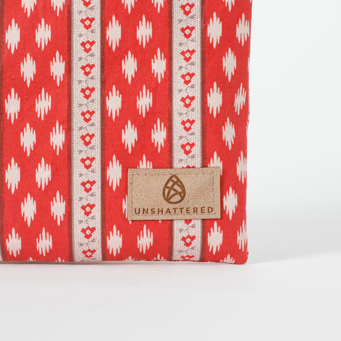 Red and white patterned zip pouch with 'Unshattered' brand label on a white background named after Neena 