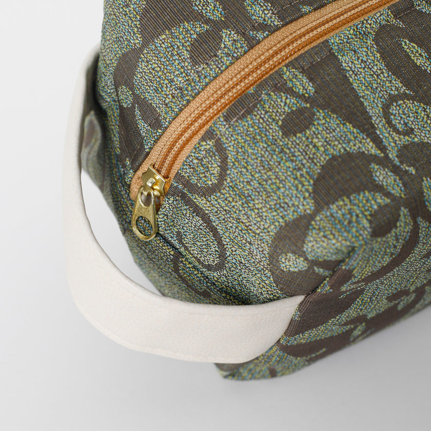 Close-up of a patterned bag with a gold zipper on a plain background