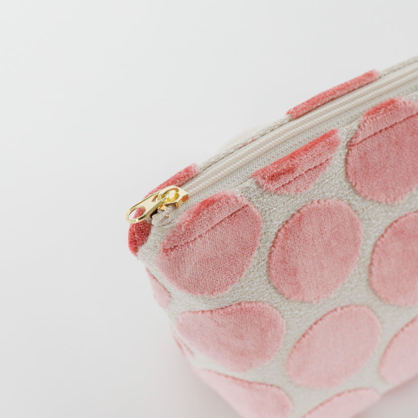 Pink polka dot makeup bag  with gold zipper on a light gray background
