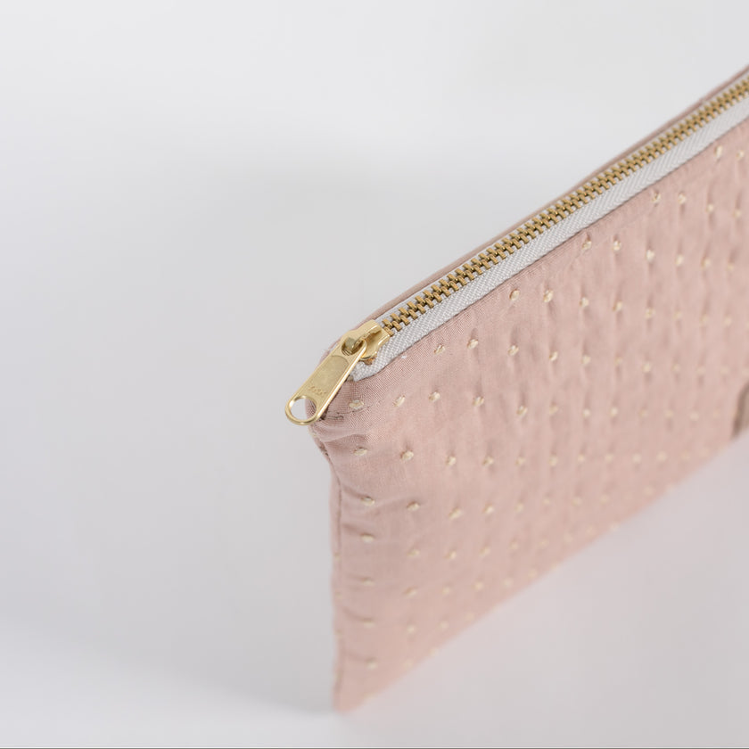 a gold toned zipper on a pink and yellow zip pouch 