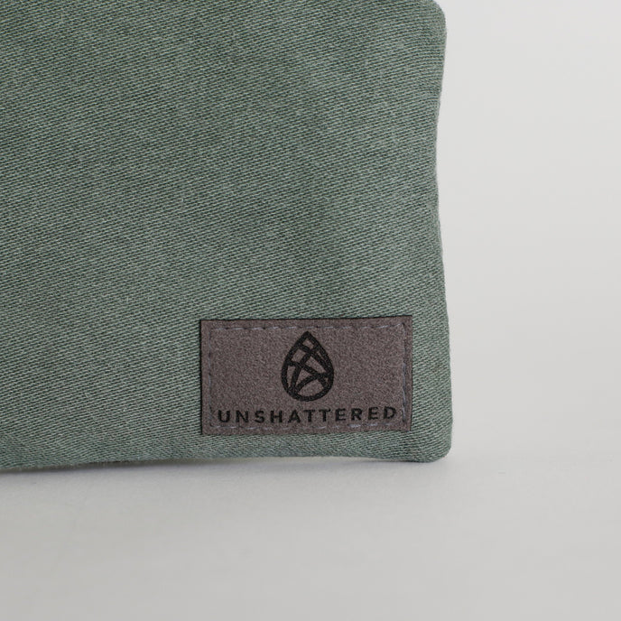 Green fabric with 'Unshattered' logo on a white background