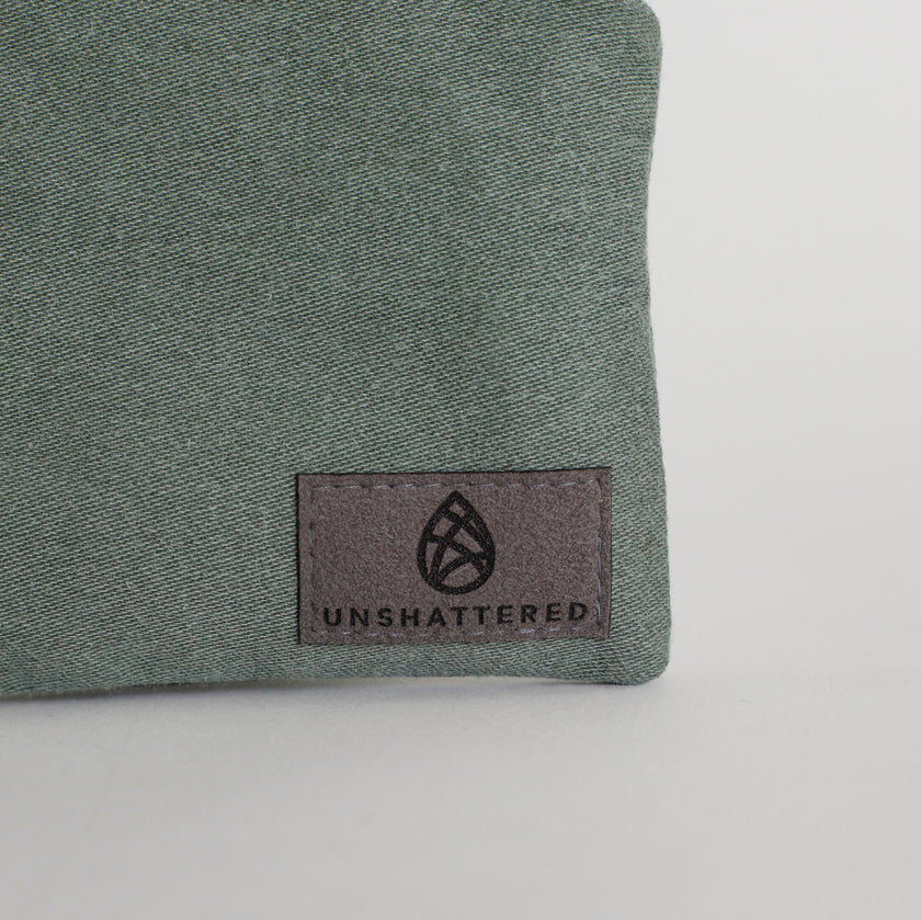Green fabric with 'Unshattered' logo on a white background