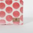 Fabric with pink polka dots and a Unshattered tan label on a white background