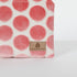 Fabric with pink polka dots and a Unshattered tan label on a white background