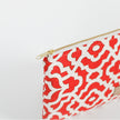 A red and white design zip pouch with a gold tone zipper
