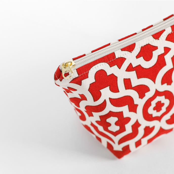 A gold tone zipper on a red and white makeup bag 
