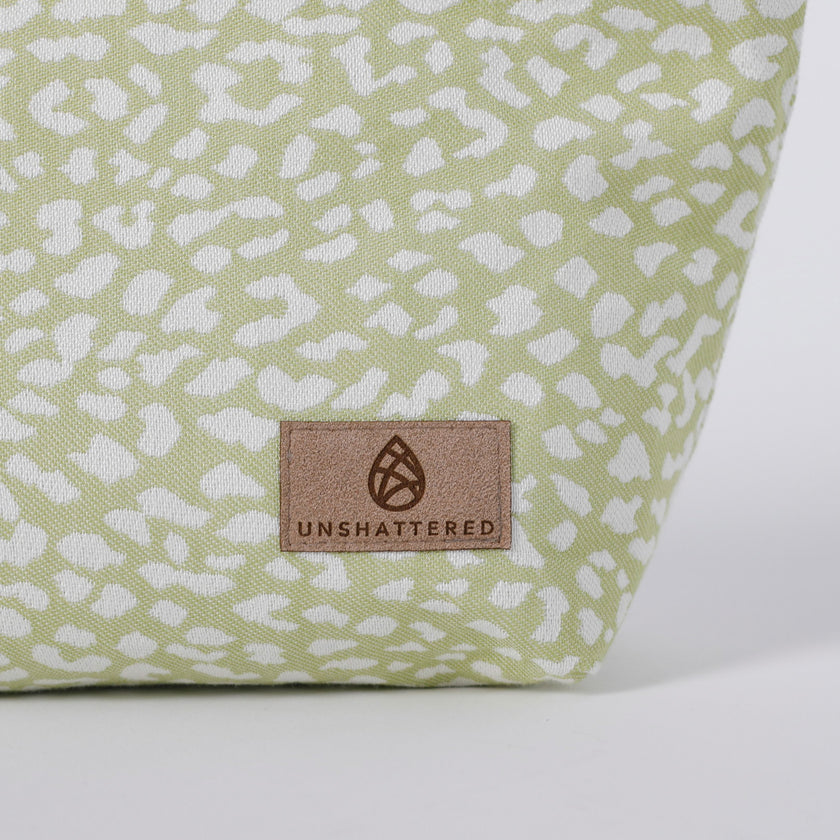 Green fabric with white pattern and 'Unshattered' brand logo on a white background named after Sky 