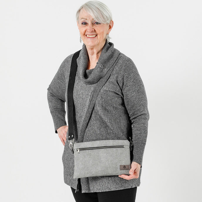 A woman wearing the Greg 3-in-1 gray bag in a crossbody style.