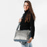 A woman wearing a charcoal luxury leather alternative handbag with blue accent named after Wanda.