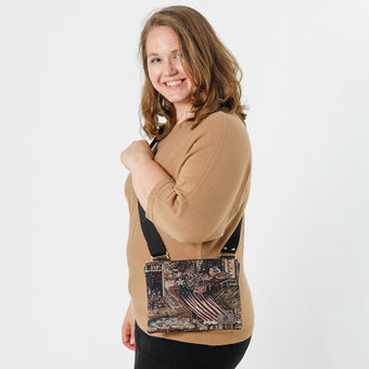 A woman carrying a cafe fabric crossbody pouch with gold hardware and a black strap 