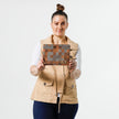 Woman holding a zippered pouch with a modern geometric square pattern in various shades of brown. 