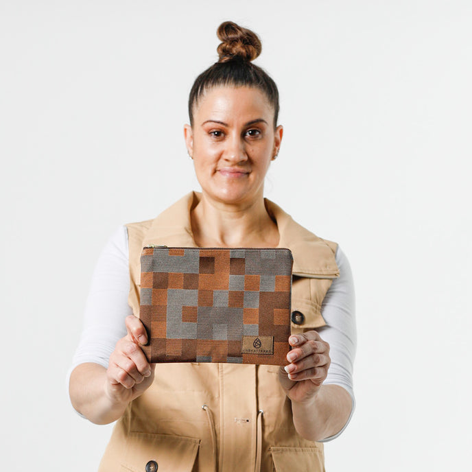 A woman holding a zippered pouch with a modern geometric square pattern in various shades of brown named after Jazzmaine.