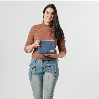 A woman holding a blue zip pouch with  a peach shell design with a tan label 