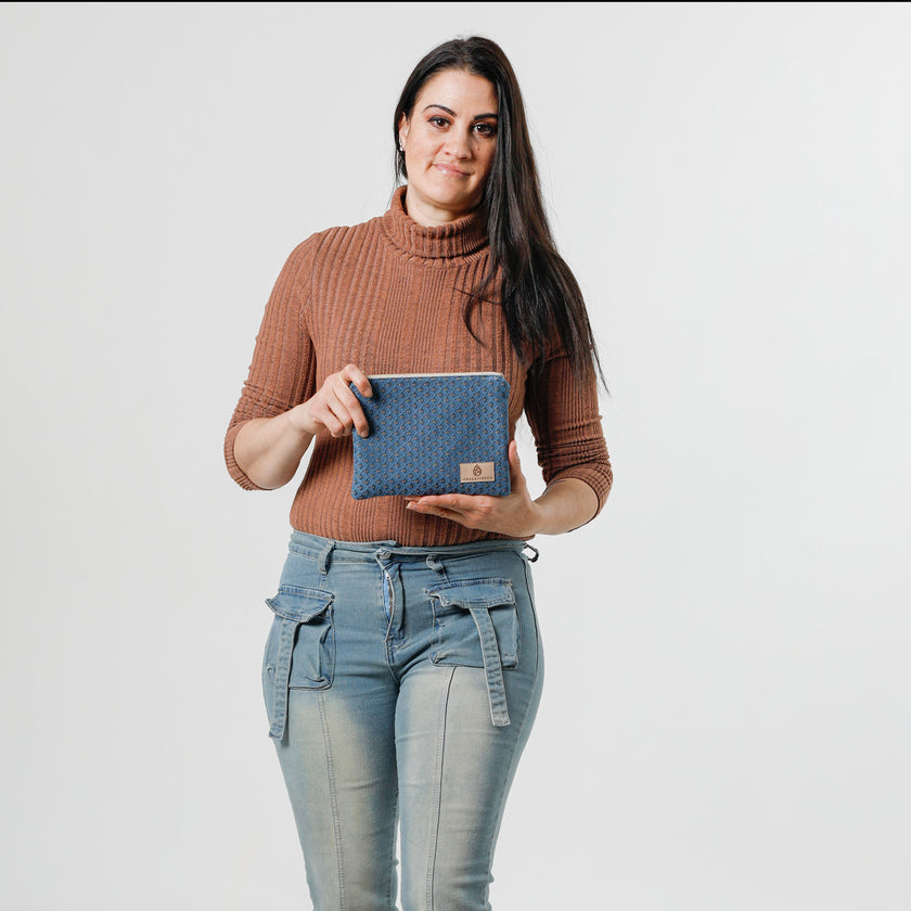 A woman holding a blue zip pouch with  a peach shell design with a tan label 