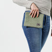Woman holding a green plush zippered pouch against her blue jeans