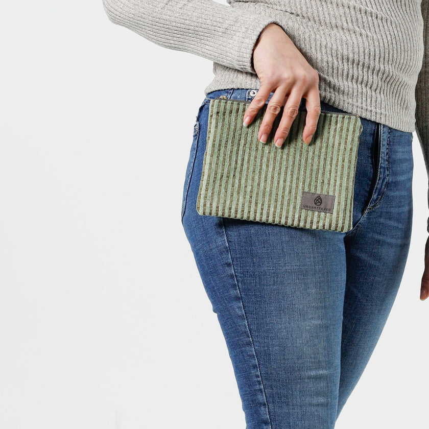 Woman holding a green plush zippered pouch against her blue jeans