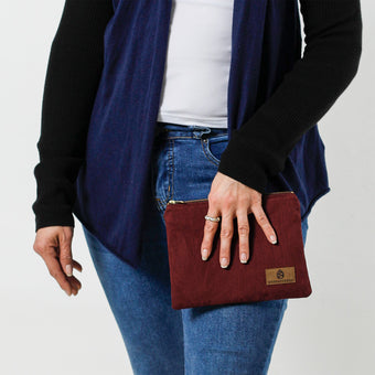 Woman holding a burgundy floral damask fabric pouch on a white background