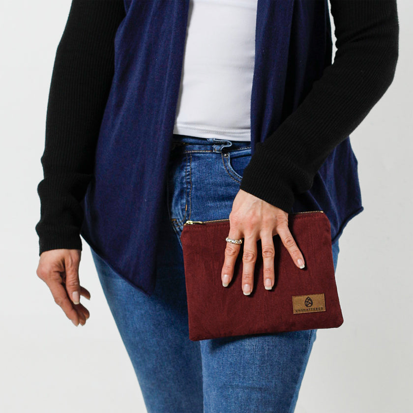 Woman holding a burgundy floral damask fabric pouch on a white background
