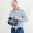 A man holding a blue leather toiletry kit with a zip closure and gold-tone hardware, made from  upcycled from Southwest Airlines seat leather.