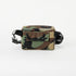 A pocket on the back of a woodland camo errand bag with black straps and black metal hardware on a white background 