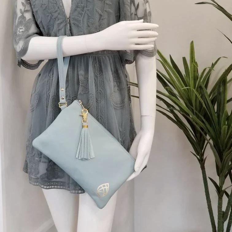 One founders edition leather wristlet hanging  on a mannequin's arm next to a plant.