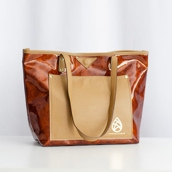 A brown and tan leather tote bag with gold-tone hardware and two leather shoulder straps, displayed against a neutral background.