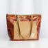 A brown and tan leather tote bag with gold-tone hardware and two leather shoulder straps, displayed against a neutral background.