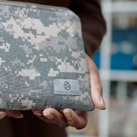 Close up of gray suede Unshattered label on a zip pouch made from upcycled US Army military uniforms